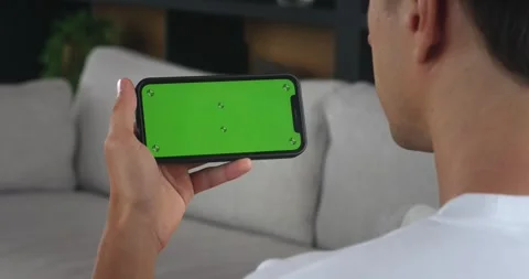 Over the shoulder shot man hand holding smartphone with horizontal green screen Stock Footage 255289038