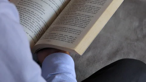 Over the shoulder shot of a man sitting on a chair and reading a book Stock Footage 146984612