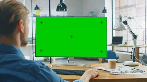 Over the Shoulder Shot: Man Uses Laptop Computer with Green Mock-up Screen Stock Footage