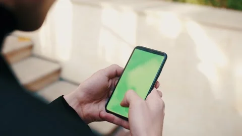 Over the shoulder shot of man using a phone with a green screen outdoors 스톡 동영상 143355510