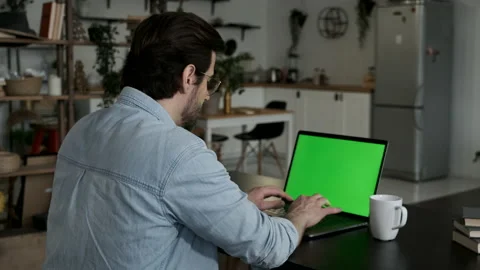 Over the shoulder shot of man working online on laptop with green screen display Stock Footage 144234041