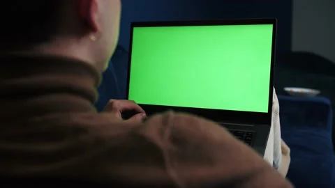Over the shoulder shot of a man working laptop on sofa at home with green screen Stock Footage 144311297