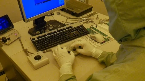 An over shoulder shot of a scientist working on a microscope in a Vidéo 94570037