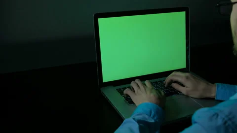 Over the shoulder shot of young man typing on a laptop with a key green screen. 库存影片 88995282