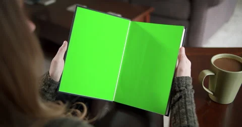 Over the shoulder slider shot of a young woman reading a book with green screen  Stock Footage 146048522