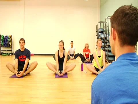 Over the shoulder of trainer with trainees stretching Stock Footage 7728179