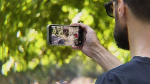 Over-the-Shoulder View of Bearded Man Filming Scene with Smartphone Video stock 342824686