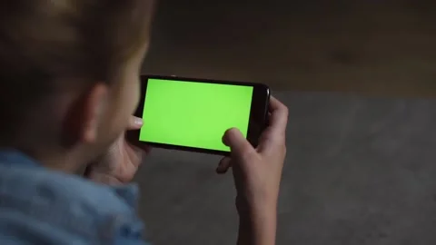 Over the shoulder view of a blank mobile phone screen held by teenage girl Stock Footage 231683736