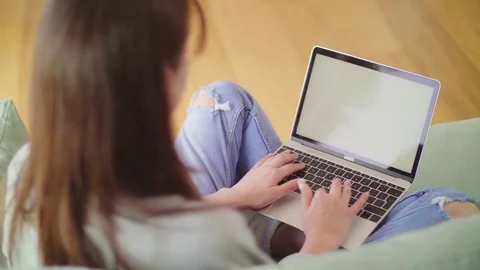 Over the shoulder view of blogger using laptop on sofa Stock Footage 79658926
