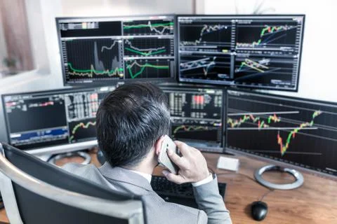 Over the shoulder view of computer screens and stock broker trading online. Stock Photos