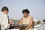 Over The Shoulder View Of A Couple Eating A Meal On A Rooftop Terrace Stock Photos