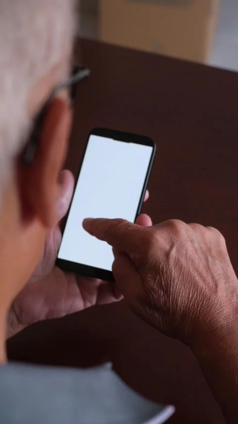 Over-the-shoulder view of an elderly man with wrinkled hands scrolling Video stock 344642966