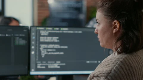 Over shoulder view of focused database designer writing code looking at multiple Stock Footage 168233410