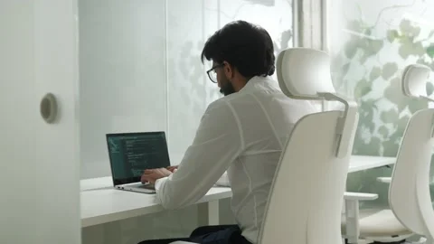 Over the shoulder view of focused qualified IT developer working in bright Stock Footage 228859423