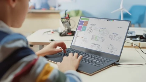 Over the Shoulder View of a Kid Using Laptop to Design and Program Robot Video stock 119565143