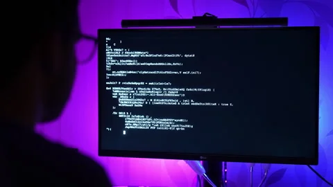 Over the shoulder view of man coding on computer with purple blue RGB lighting Stock Footage 325803818