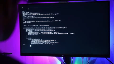 Over the shoulder view of man coding on computer with purple blue RGB lighting Vídeos de archivo 325803819