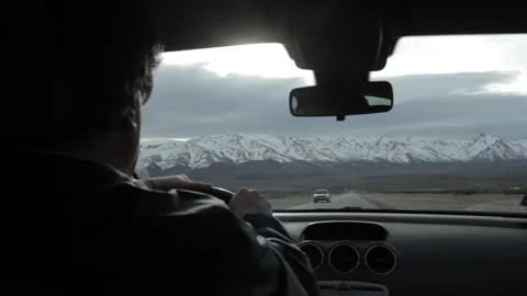 Over The Shoulder View Of Man Driving Towards Snowy Andes Mountains Stock Footage 336623984