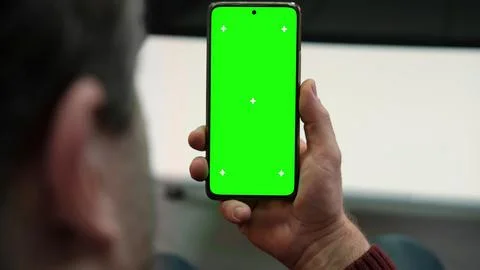Over the shoulder view of man holding smartphone vertically with green scre.. Stock-Fotos