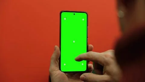 Over the shoulder view of man holding smartphone vertically with green scre.. Fotos Stock