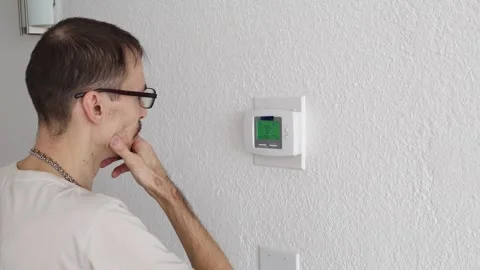 Over shoulder view of man pressing button on home thermostat Stock Footage 330555918