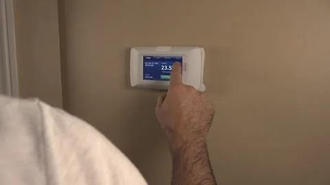 Over-the-Shoulder View of a Man Programming a Smart Wall Thermostat Stock Footage 348686795