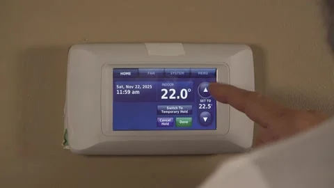 Over-the-Shoulder View of a Man Programming a Smart Wall Thermostat Stock Footage 348686928