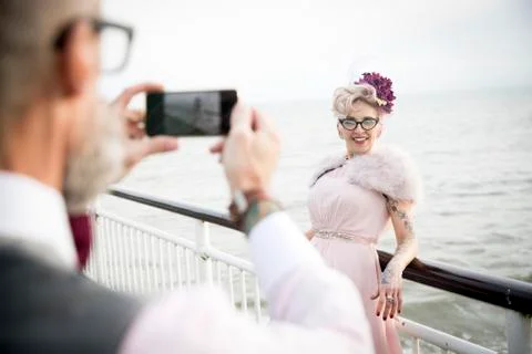 Over shoulder view of man taking photograph of 1950's vintage style mature woman Fotos Stock