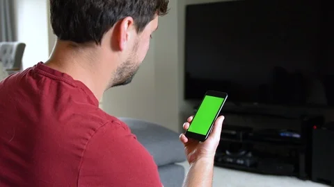 Over shoulder view of man using phone with green screen Stock Footage 92285933