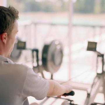 Over the shoulder view of man using rowing machine Stock Photos