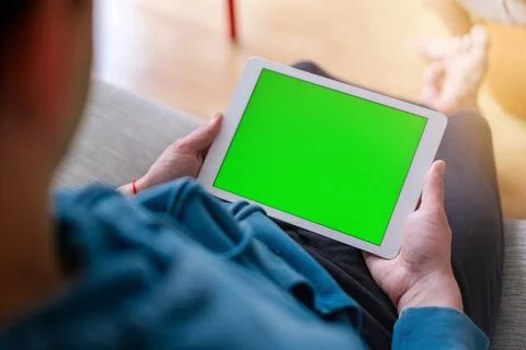 Over the shoulder view of a man working on a tablet with a green chroma key Stock Photos