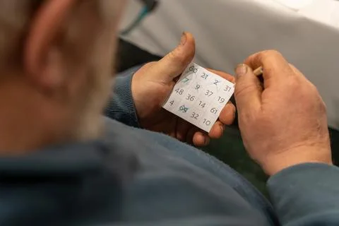 Over the shoulder view of old man holding bingo card with numbers Fotos Stock