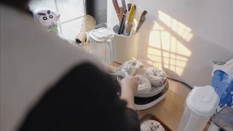 Over the shoulder view of a person preparing freshly made bagels in a small pan, Видео 328983638