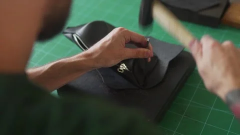Over shoulder view of professional leather craftsman at work table making Stock Footage 256994867