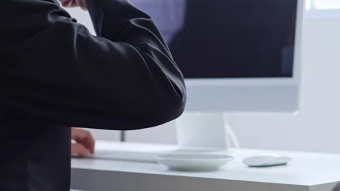 Over-the-shoulder view of professional working at computer while drinking coffee Stock Footage 328550932