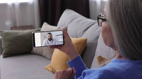 Over shoulder view of sick senior woman patient at home using smartphone for Stock Footage 196168817