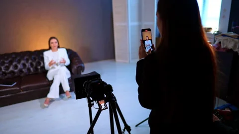 Over the shoulder view of smartphone filming interview. Person recording woman Stock Footage 329192516