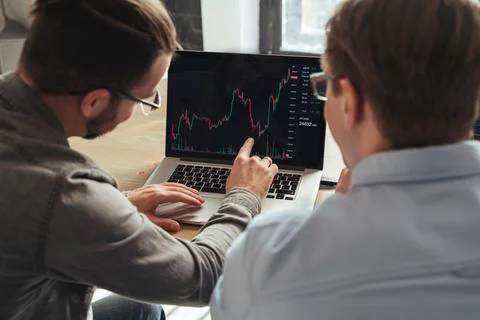 Over shoulder view of trader couch teaching another man basics of cryptocurrency Stock Photos