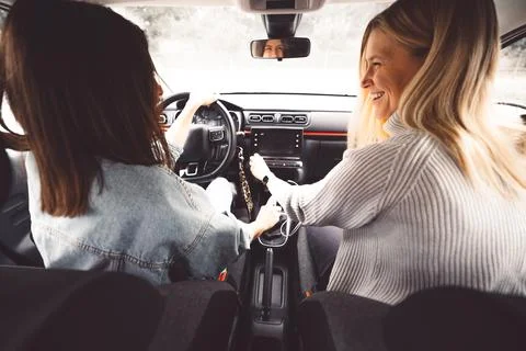 Over the shoulder view two young women sitting in the car driving in the city Stock Photos