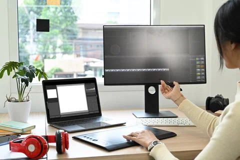 Over shoulder view of video editor editing video footage on personal computer at Stock Photos