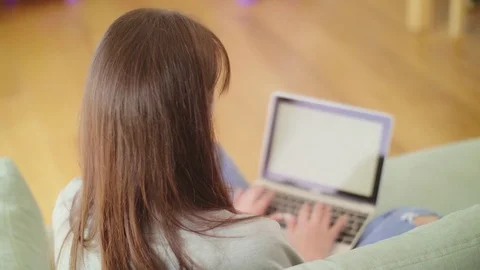 Over the shoulder view of woman using laptop on sofa Stock Footage 79658945