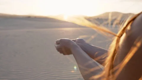 Over the shoulder view of womans hands releasing desert sand Stock Footage 125972185