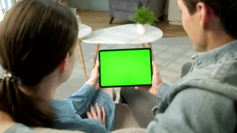 Over The Shoulder View Young Couple at Home Sitting on a Sofa Using With Green Stock Footage 133285393