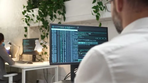 Over-the-shoulder view of young professional successful male programmer coding Stock Footage 228984394
