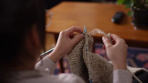 Over the shoulder of a woman using a needle point to crochet a scarf Video stock 129043743