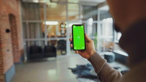 Over the shoulder young man using smartphone mock-up vertical chroma key display Stock Footage 128246975