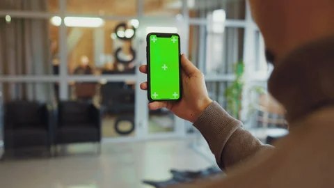 Over the shoulder young modern man using a smartphone with vertical chrome key Stock Footage 128247307