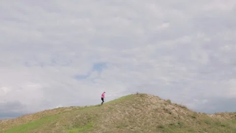 Overall or long shot of young woman in sportswear running up hill Stock Footage 193989992