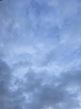 Overcast blue evening sky background with soft clouds. Stock Photos