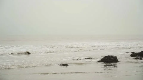 Overcast day on the beach with the small waves and muddy water 動画素材 169523152